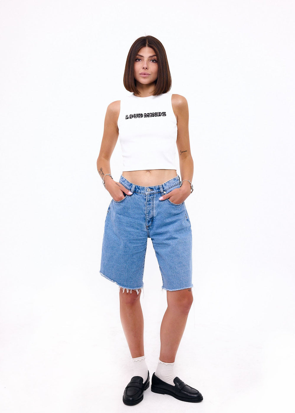 Woman wearing a white crop top and blue denim shorts on a white background