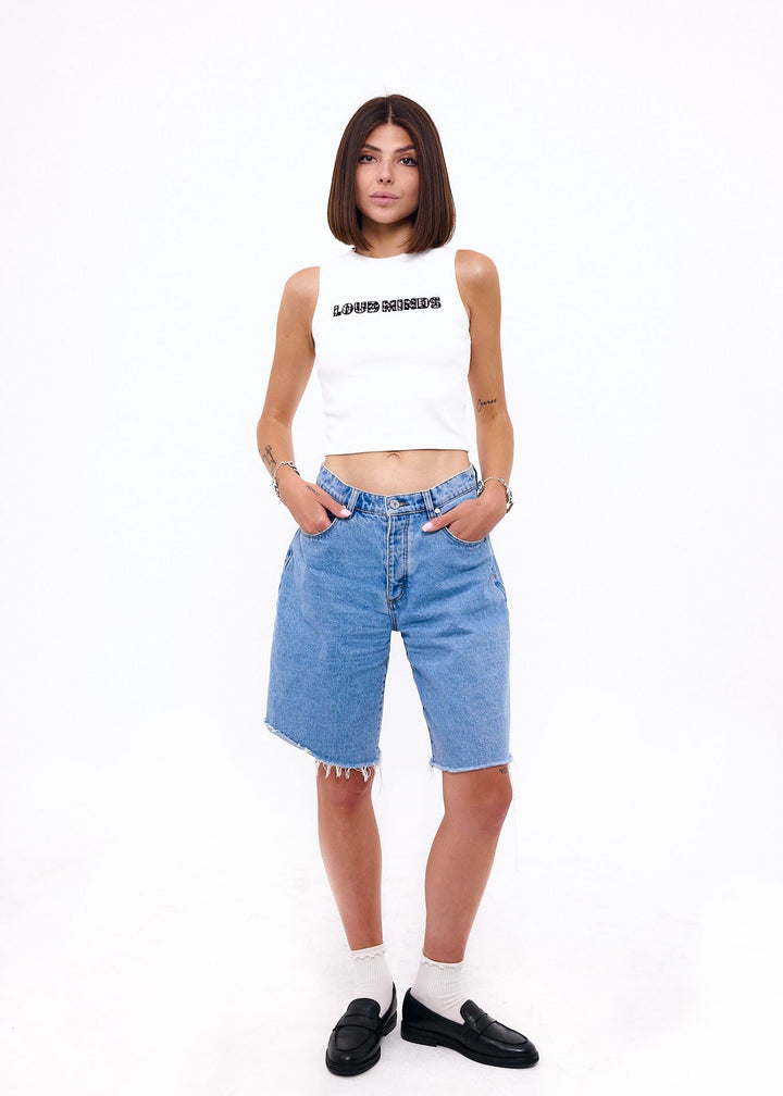 Woman wearing a white crop top and blue denim shorts on a white background
