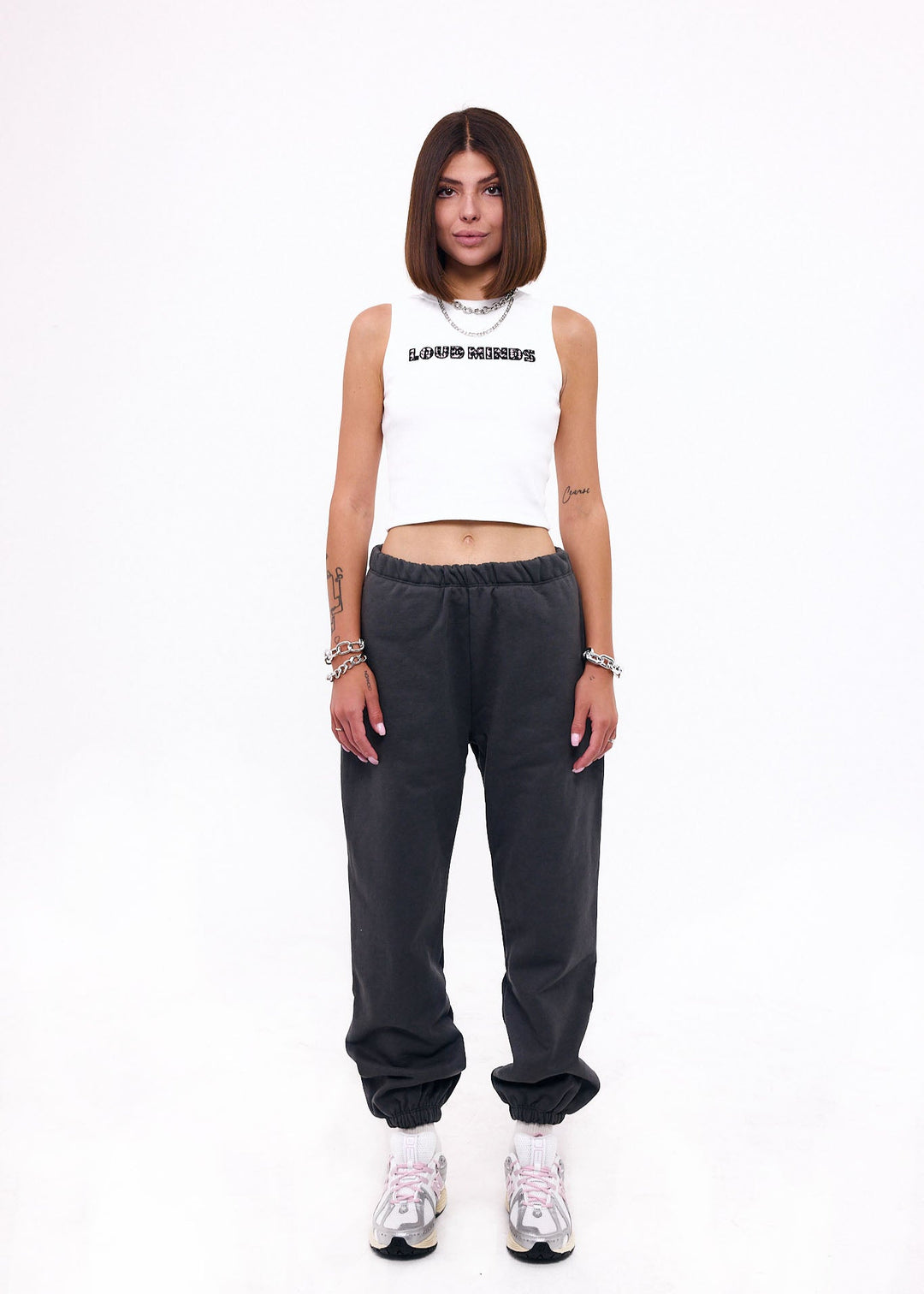 Person wearing a white tank top and dark gray pants on a white background