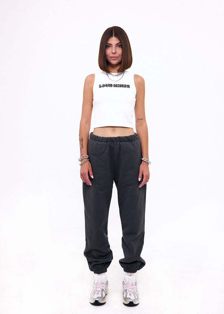 Person wearing a white tank top and dark gray pants on a white background