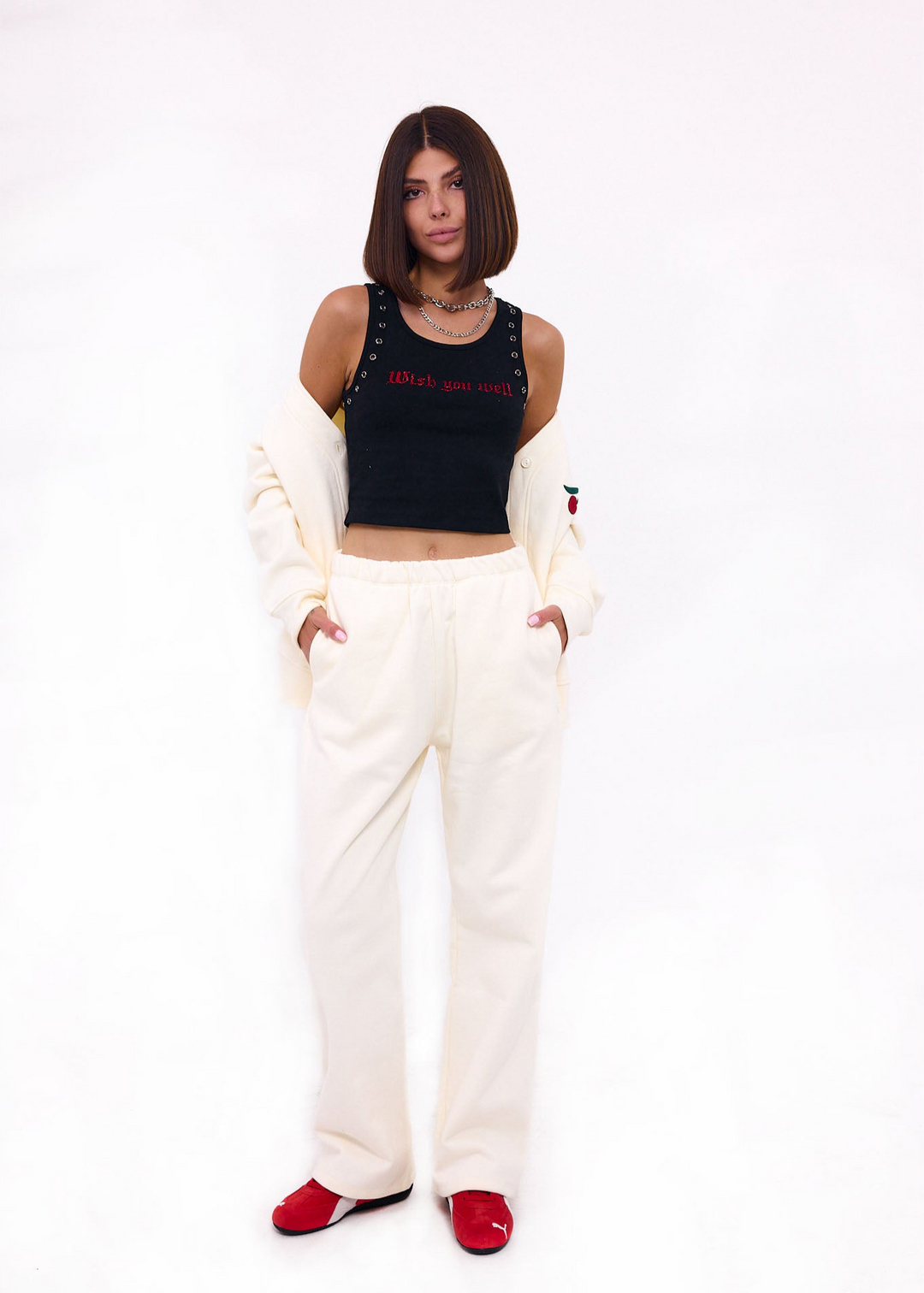 Woman wearing a black crop top with text and white pants on a white background