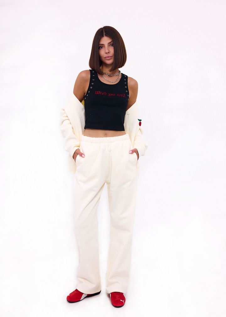 Woman wearing a black crop top with text and white pants on a white background