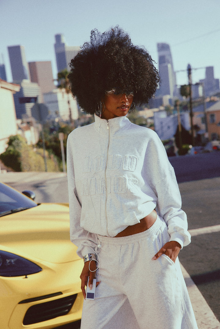 Person wearing a heather grey fleece outfit with a cityscape in the background