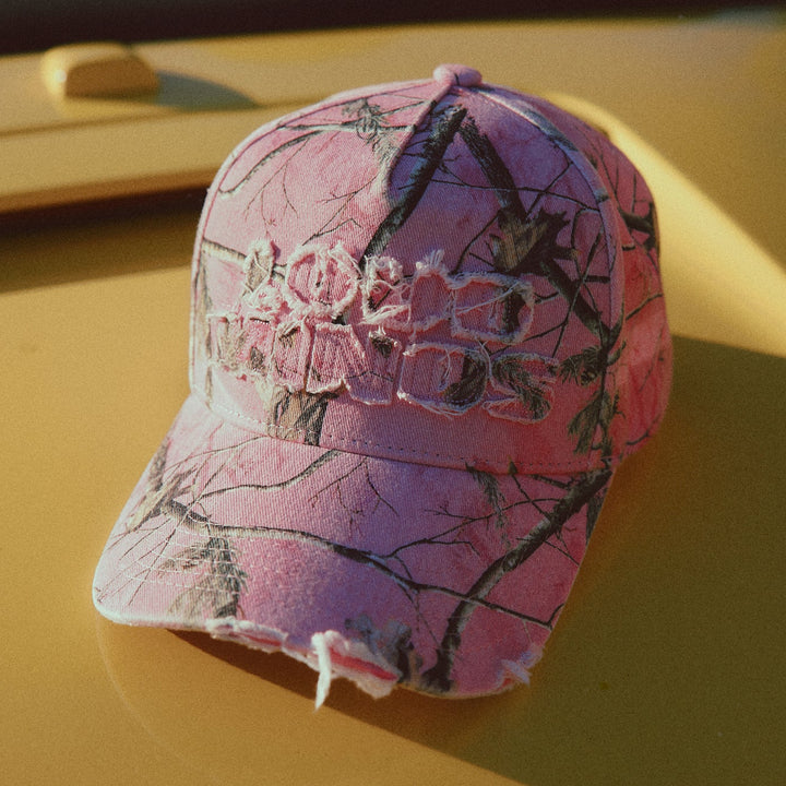 Pink camouflage baseball cap on a yellow surface
