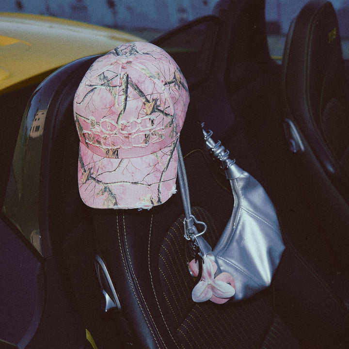 Pink cap and silver handbag hanging from a car seat in a vehicle interior.